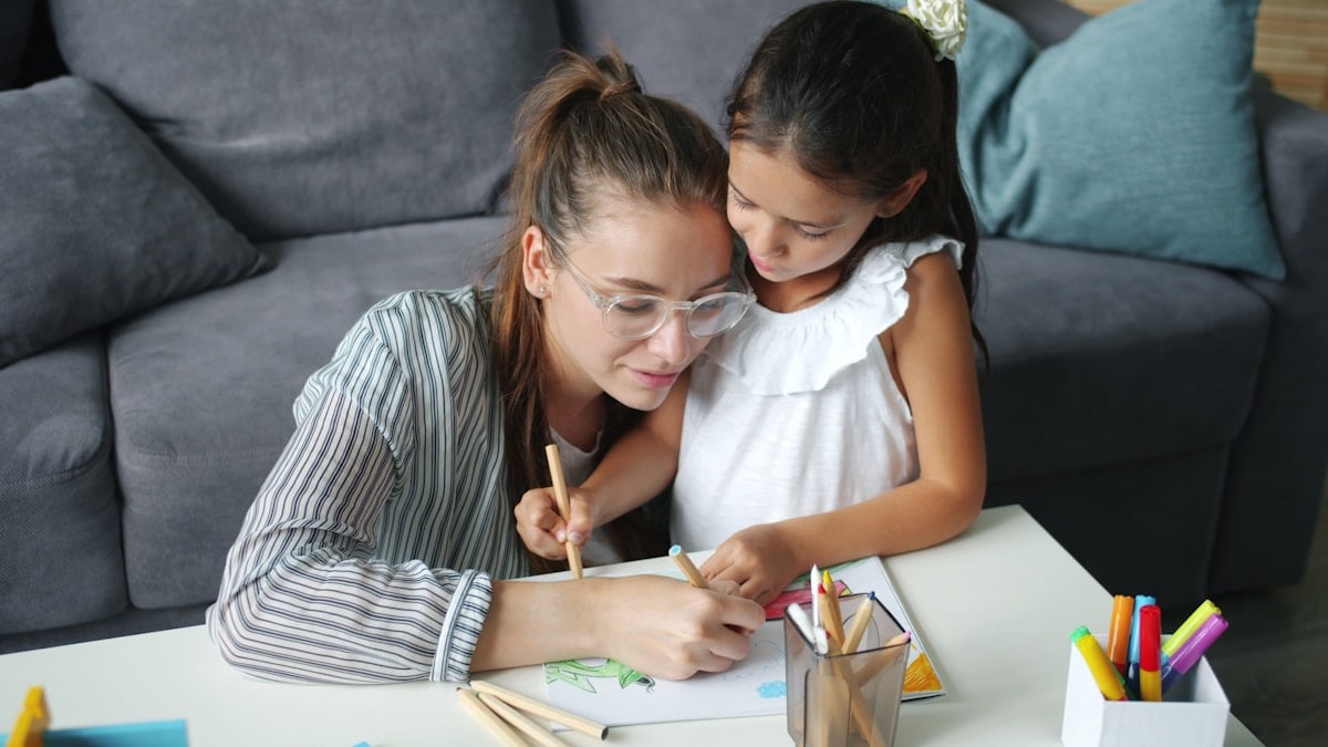 Adorable child and pretty young woman are drawing picture at home enjoying art and leisure time in house together. Family activities, children and happiness concept.